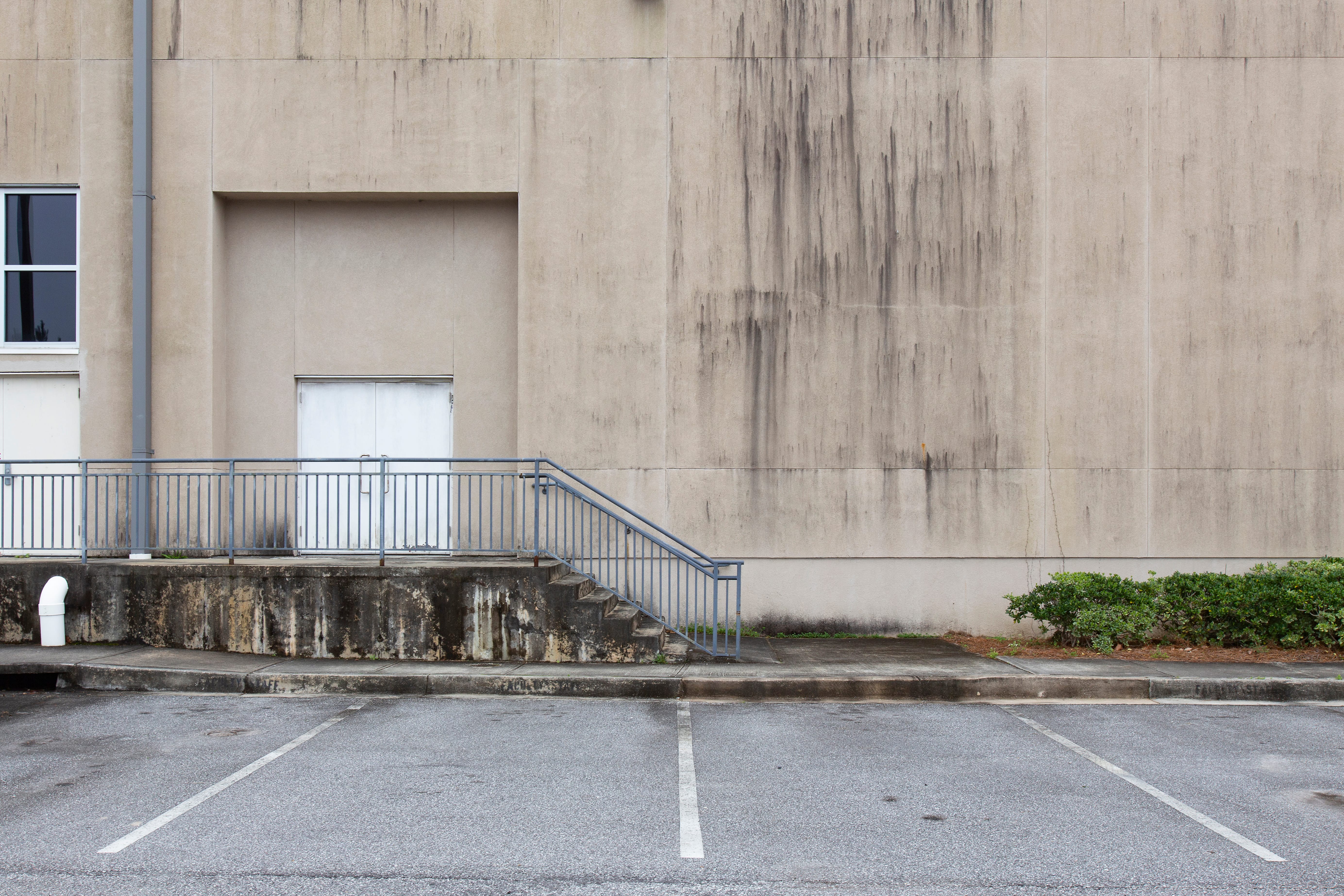 stairs,and,handrail,to,entrance,to,concrete,building,with,mold